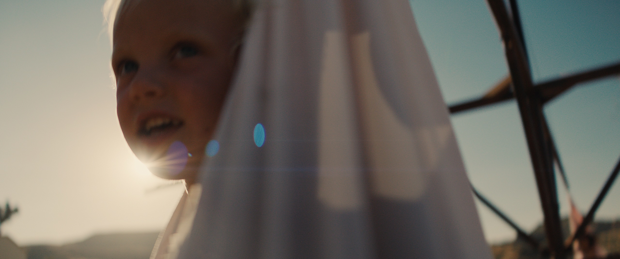 The Golden Hour — a child emerging from a veil into golden-hour sun flare, film still written and directed by Zane Ra